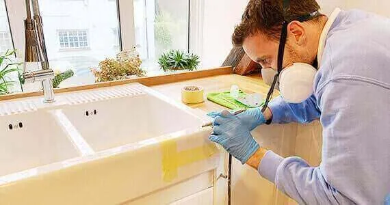 Surface Doctor technician repairing a ceramic kitchen sink